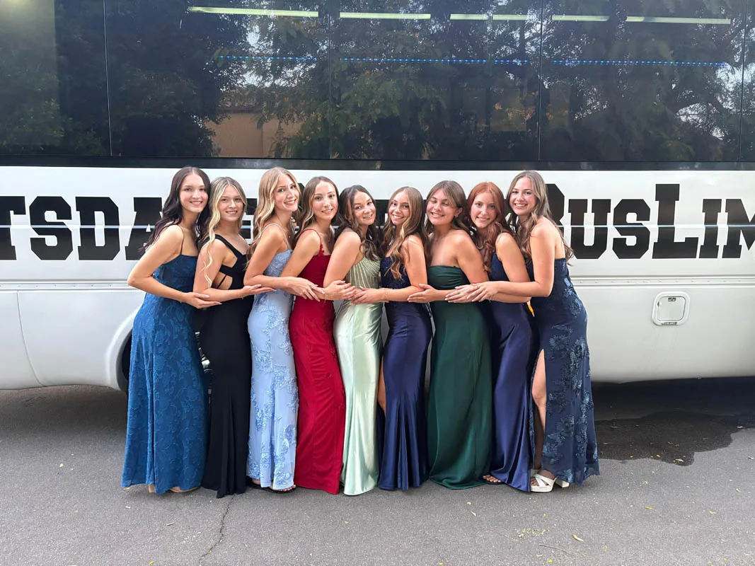 Students taking prom photos in front of a Scottsdale party bus before a prom transportation experience